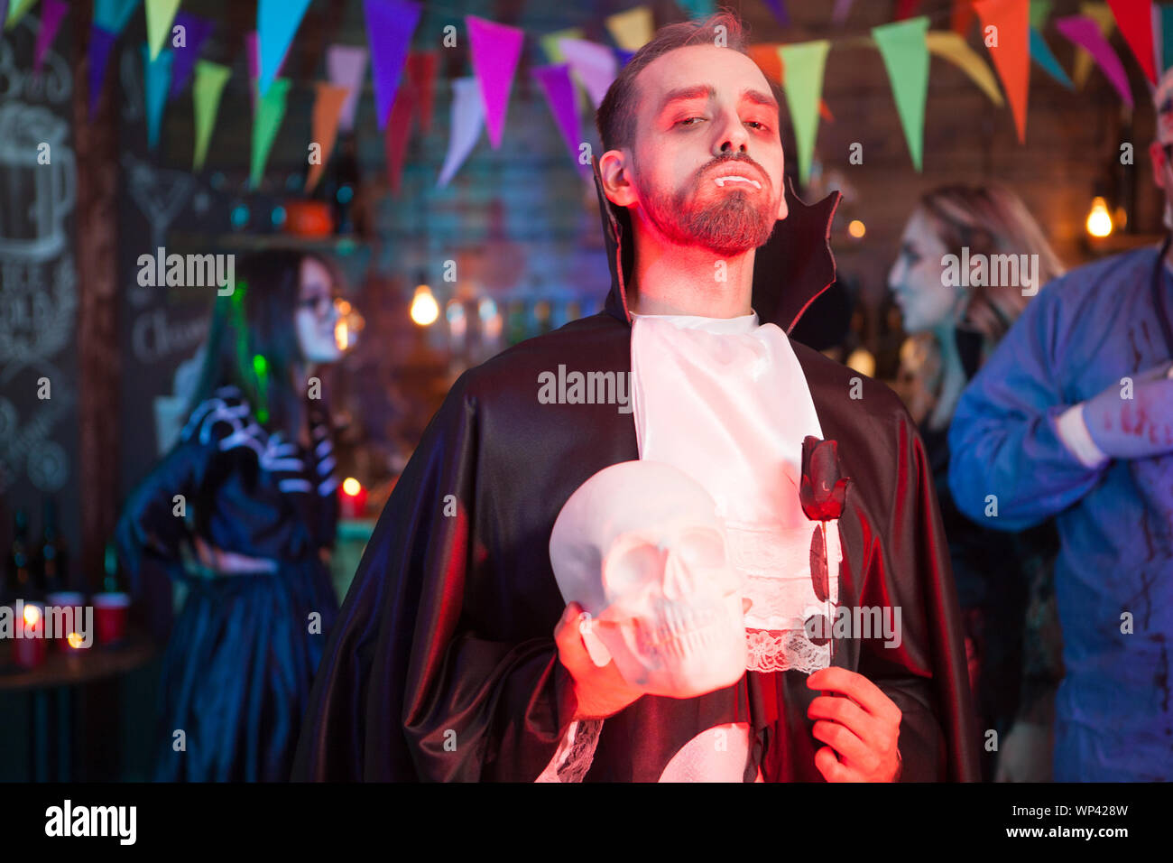 Giovane uomo vestito come un vampiro alla festa di Halloween. Egli è in possesso di uno scheletro in mani Foto Stock