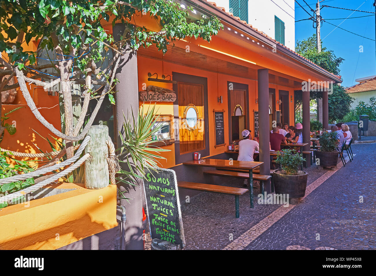 Il Jardim do Mer, Madera e persone sedersi al di fuori di un piccolo bar locale nel villaggio. Foto Stock