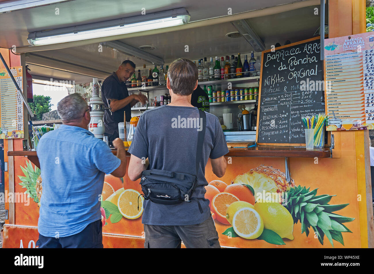 Persone che acquistano Poncha, un locale la bevanda alcolica, da un venditore ambulante di Funchal, Madeira Foto Stock