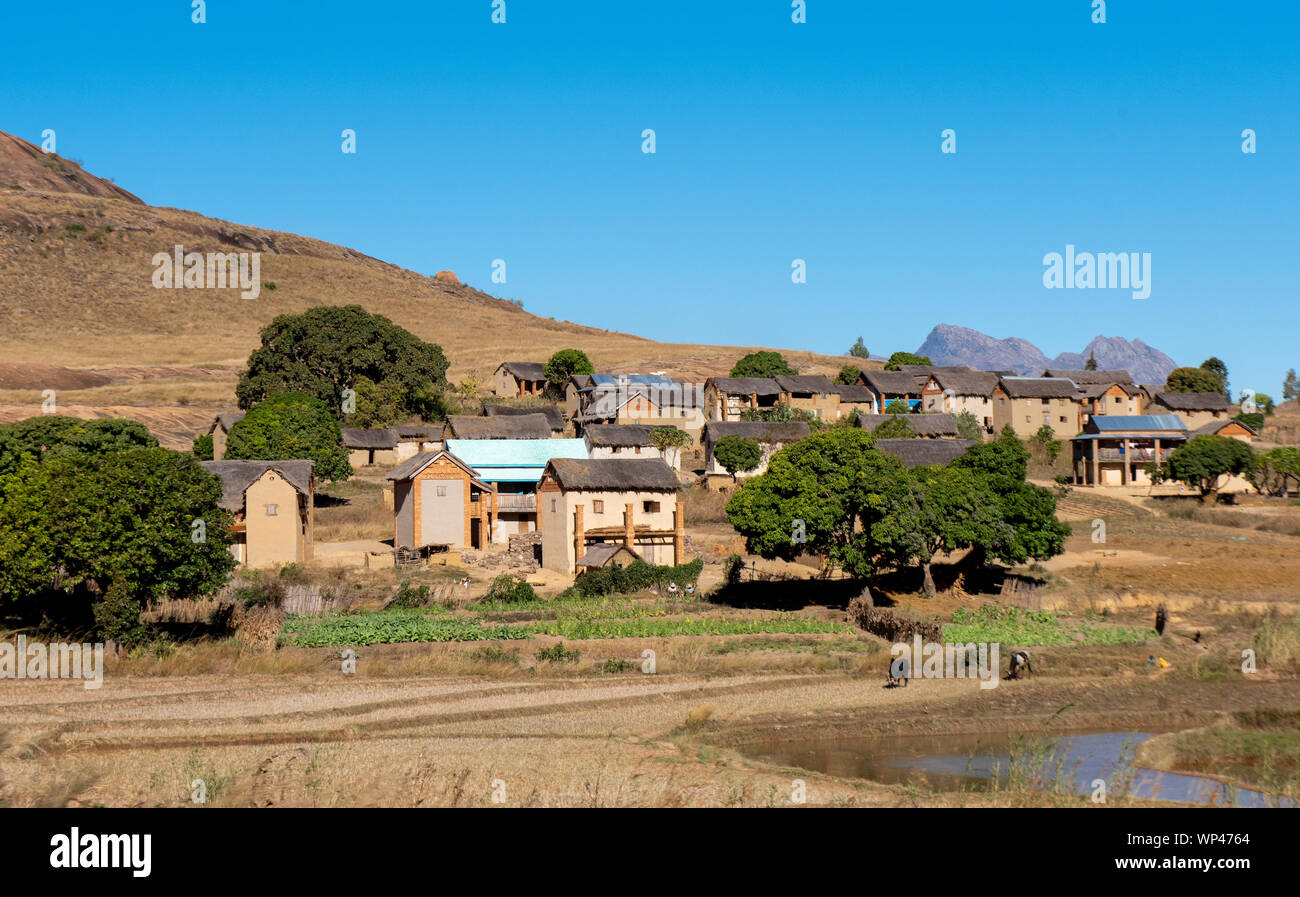 Piccolo villaggio nel sud ovest altipiani del Madagascar con tipica costruita in mattoni di erba case in paglia la coltivazione del riso e delle montagne Foto Stock