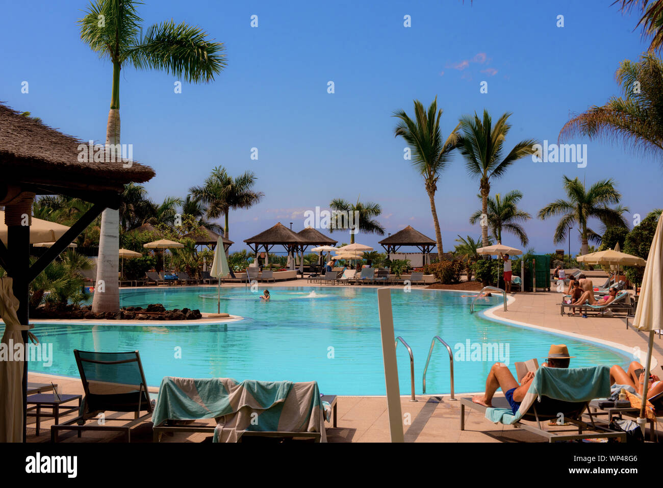 Tenerife, Isole Canarie, Spagna 6 ottobre 2018: Hotel di lusso sulla costa con palme, piscina Polonia turisti non identificati prendere il sole. Foto Stock