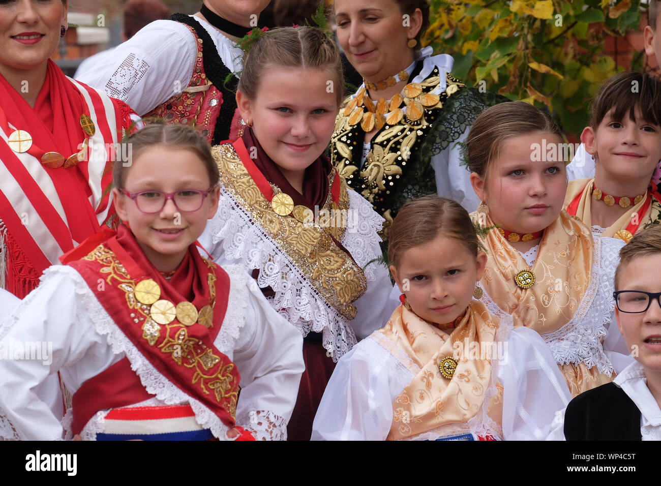 Ragazze vestito in costumi folcloristici andare in chiesa durante la Santa Messa il giorno del Ringraziamento in Stitar, Croazia Foto Stock