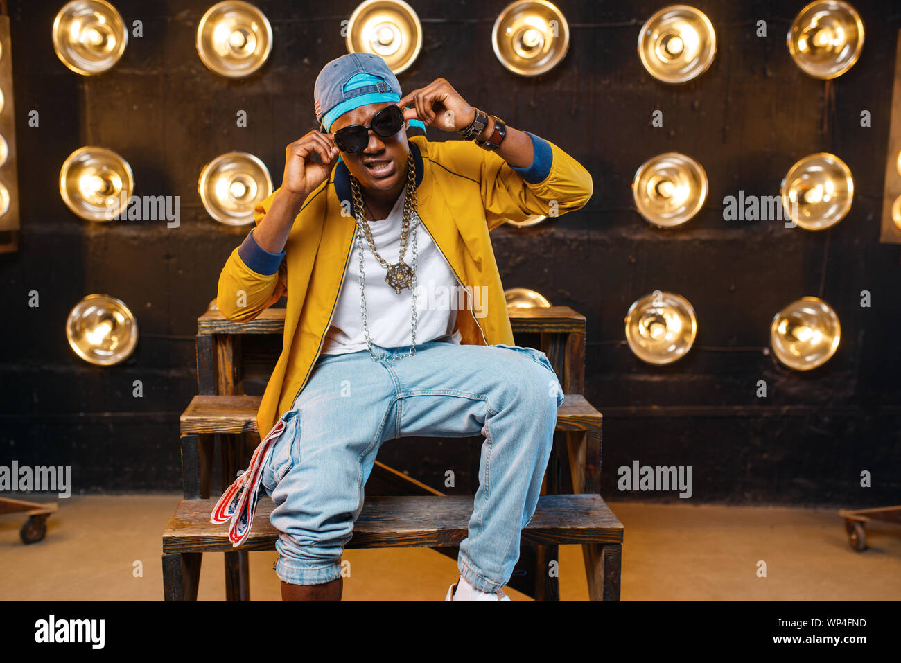 Il rapper nel cappello e occhiali da sole seduti sui gradini Foto Stock