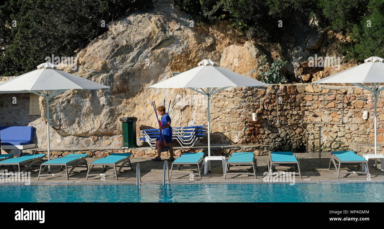 Un pulitore lavora presso una piscina dell'hotel. Foto Stock