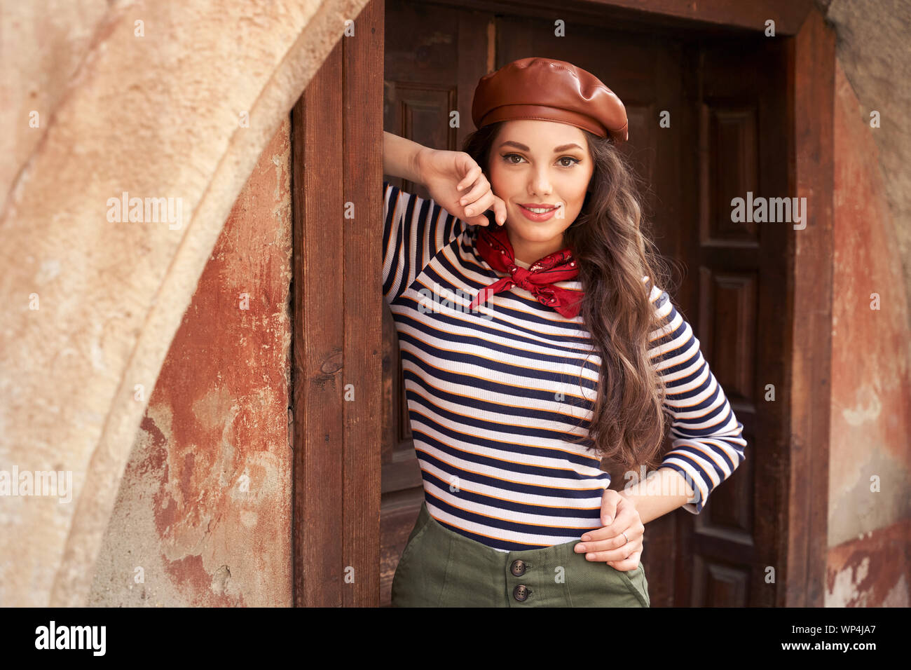 Giovane bella bruna ragazza vestita rétro in stile vintage nella vecchia città europea in piedi nel telaio della porta Foto Stock