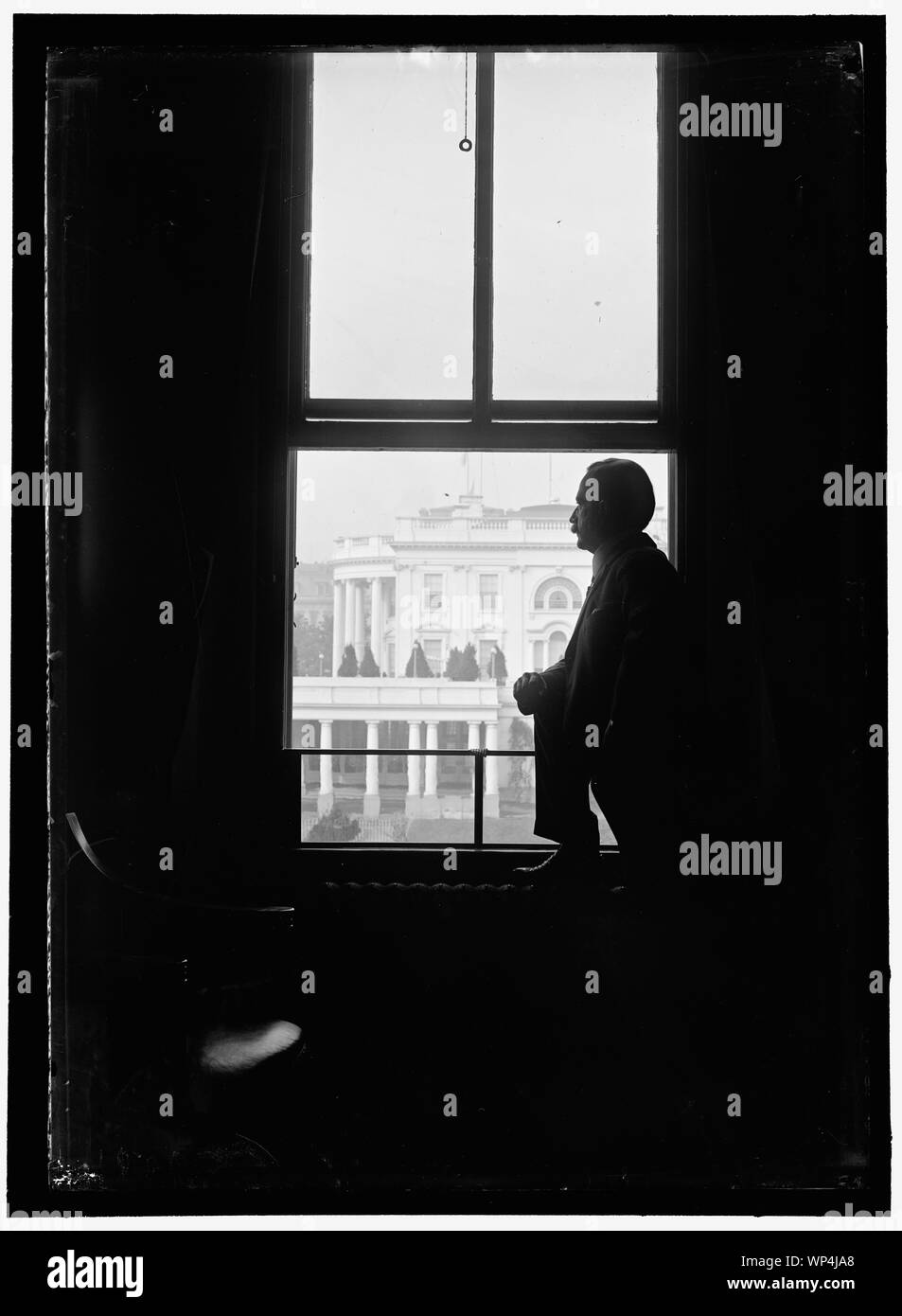 John Skelton Williams a finestra con casa bianca visibile in background, Washington, D.C. Foto Stock