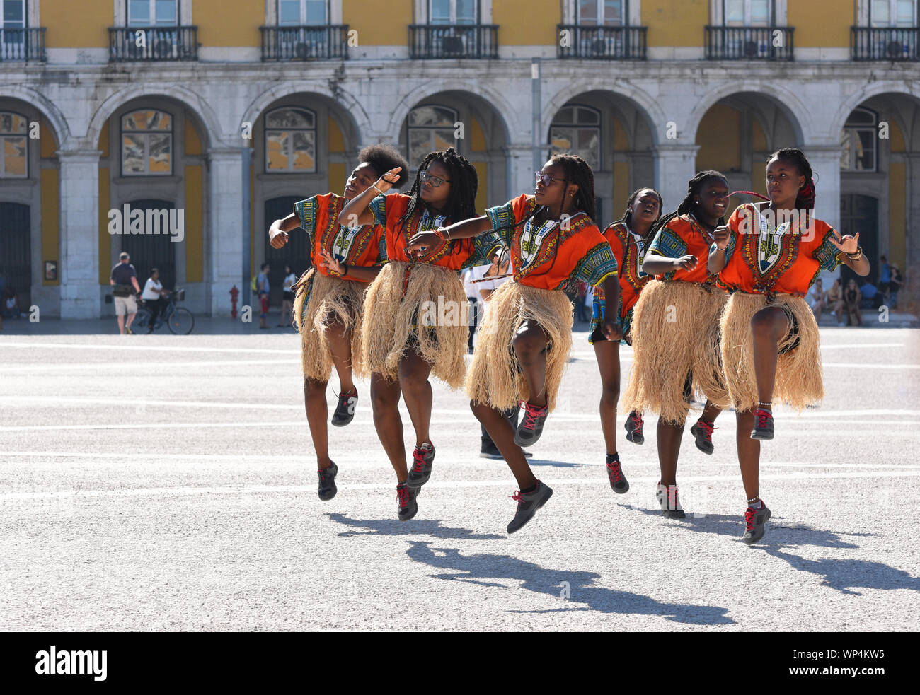 Una truppa di sei giovani donne praticanti un stile culturale dance routine in stile africano costumi a Lisbona la piazza del Commercio nel quartiere di Baixa Foto Stock