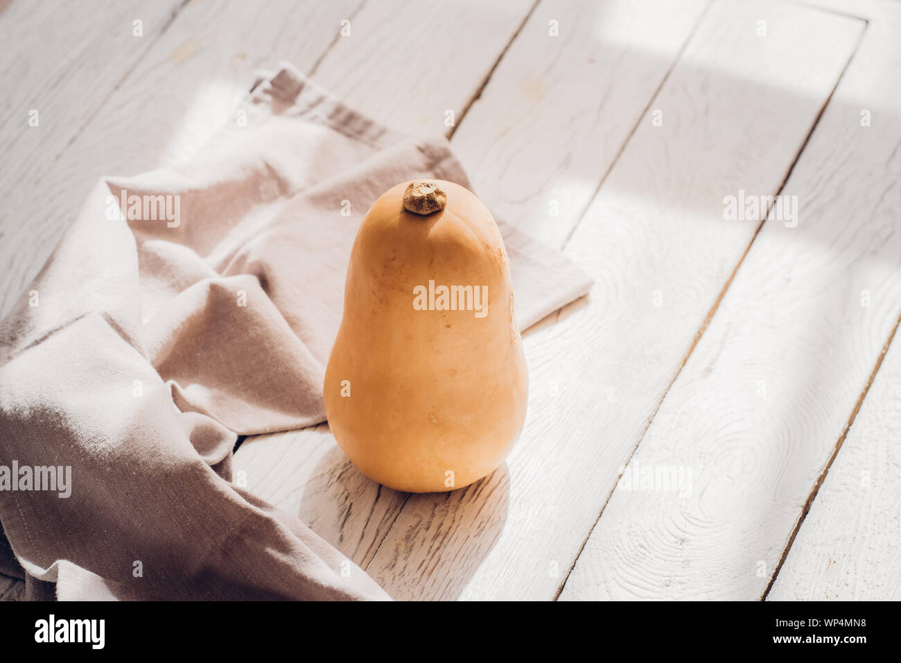 Un po' di butternut con biancheria cucina towl bianco su sfondo di legno. Stagionale autunno still life, cadono minimalismo il concetto di blogging. Spazio vuoto fo Foto Stock