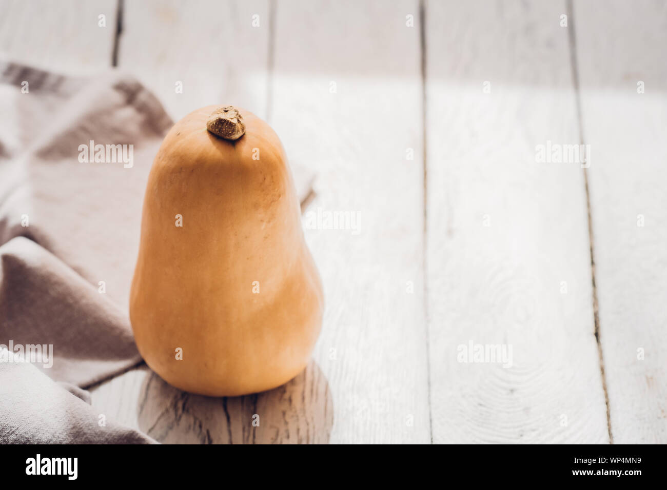 Un po' di butternut con biancheria cucina towl bianco su sfondo di legno. Stagionale autunno still life, cadono minimalismo il concetto di blogging. Spazio vuoto fo Foto Stock