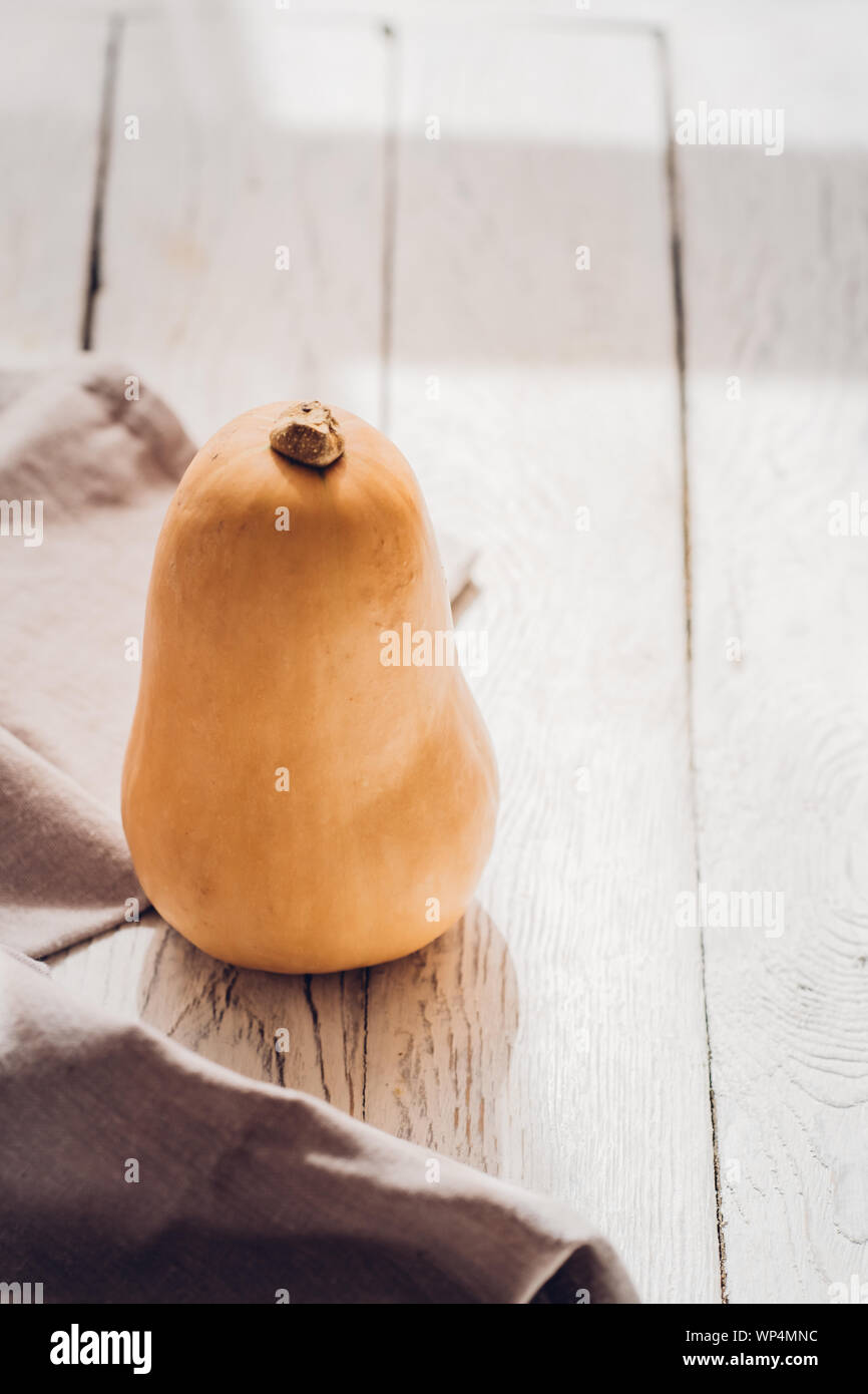 Un po' di butternut con biancheria cucina towl bianco su sfondo di legno. Stagionale autunno still life, cadono minimalismo il concetto di blogging. Spazio vuoto fo Foto Stock