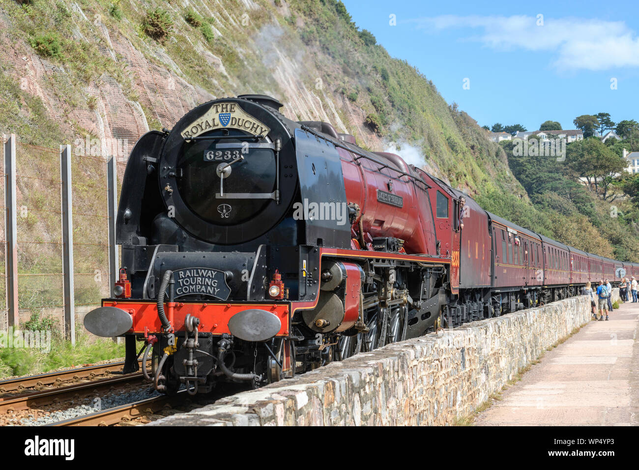Locomotiva a vapore 6233 Duchessa di Sutherland con il Royal Ducato treno passa lungo la parete del mare Teignmouth South Devon UK. Foto Stock