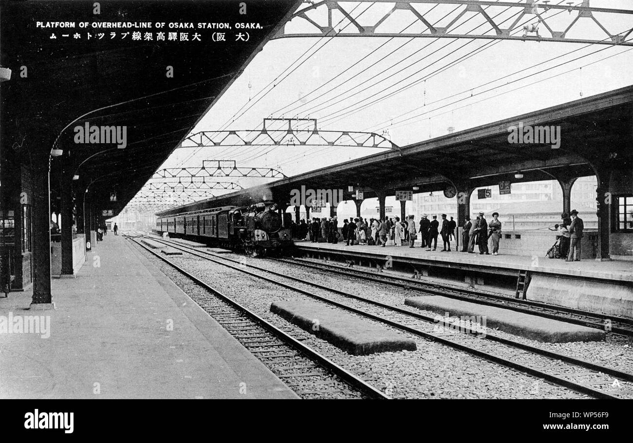[ 1930 Giappone - locomotiva a vapore nella Stazione di Osaka ] - una locomotiva a vapore tirando sei automobili arriva in corrispondenza della piattaforma aerea della Stazione di Osaka. Xx secolo cartolina vintage. Foto Stock