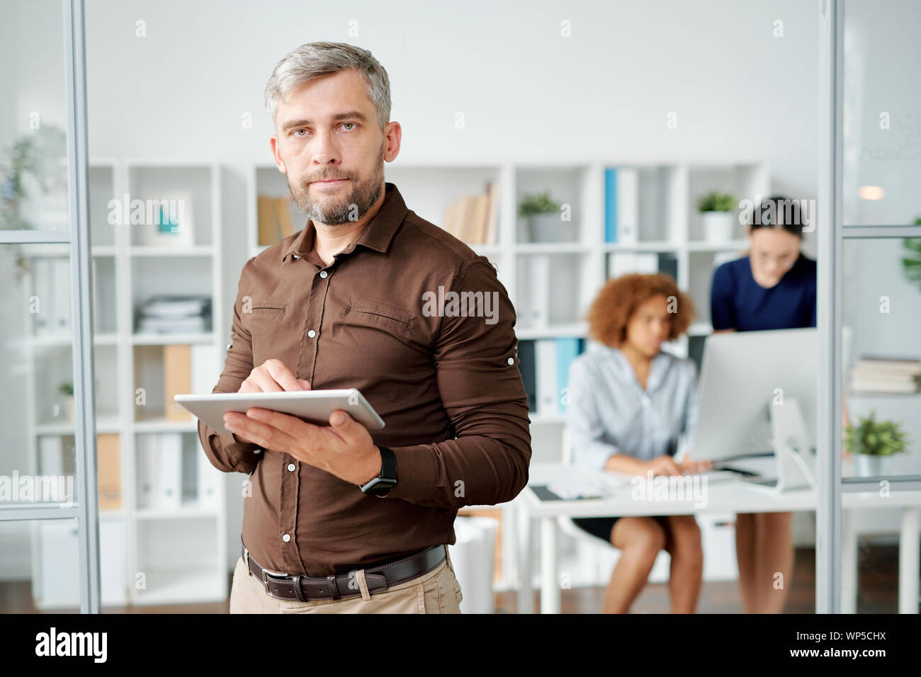 Imprenditore gravi in smart casual guardando a voi in ambiente office Foto Stock
