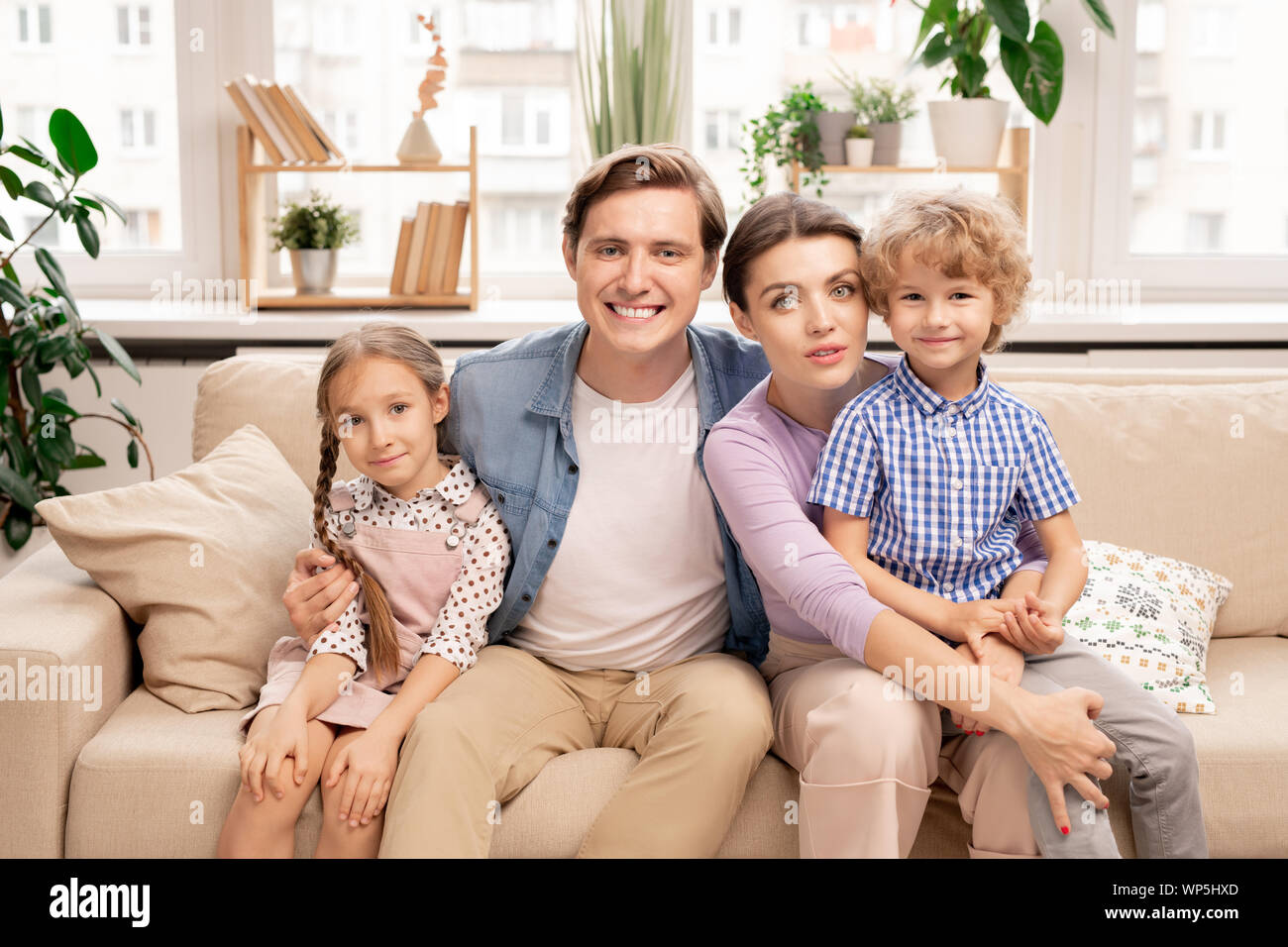 La famiglia felice di quattro in informale seduti sul divano in soggiorno Foto Stock