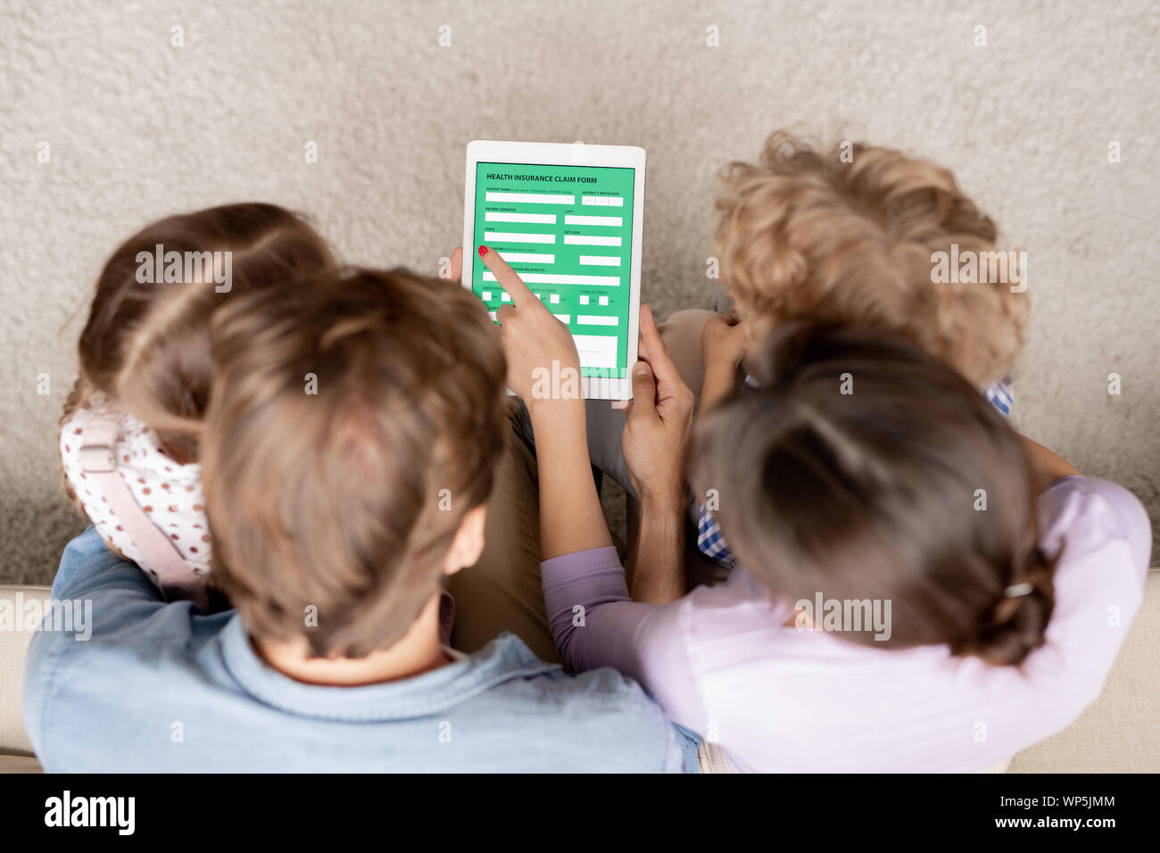 Giovane famiglia contemporanea di quattro con tavoletta digitale il riempimento in forma elettronica Foto Stock