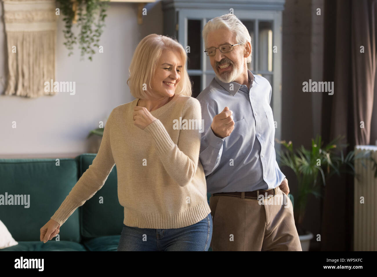 Attivo coppia senior divertiti ballando in salotto Foto Stock