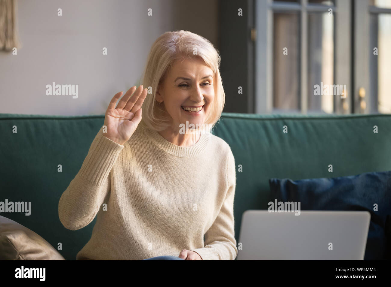 Sorridente donna matura talk su chiamata video su laptop Foto Stock
