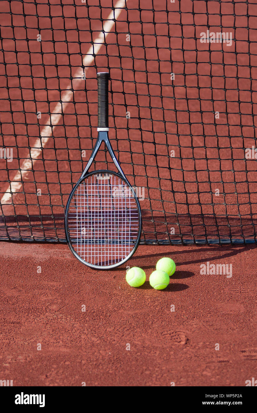 Ancora la vita di palle da tennis e una racchetta su un campo da tennis in argilla rossa. Foto Stock