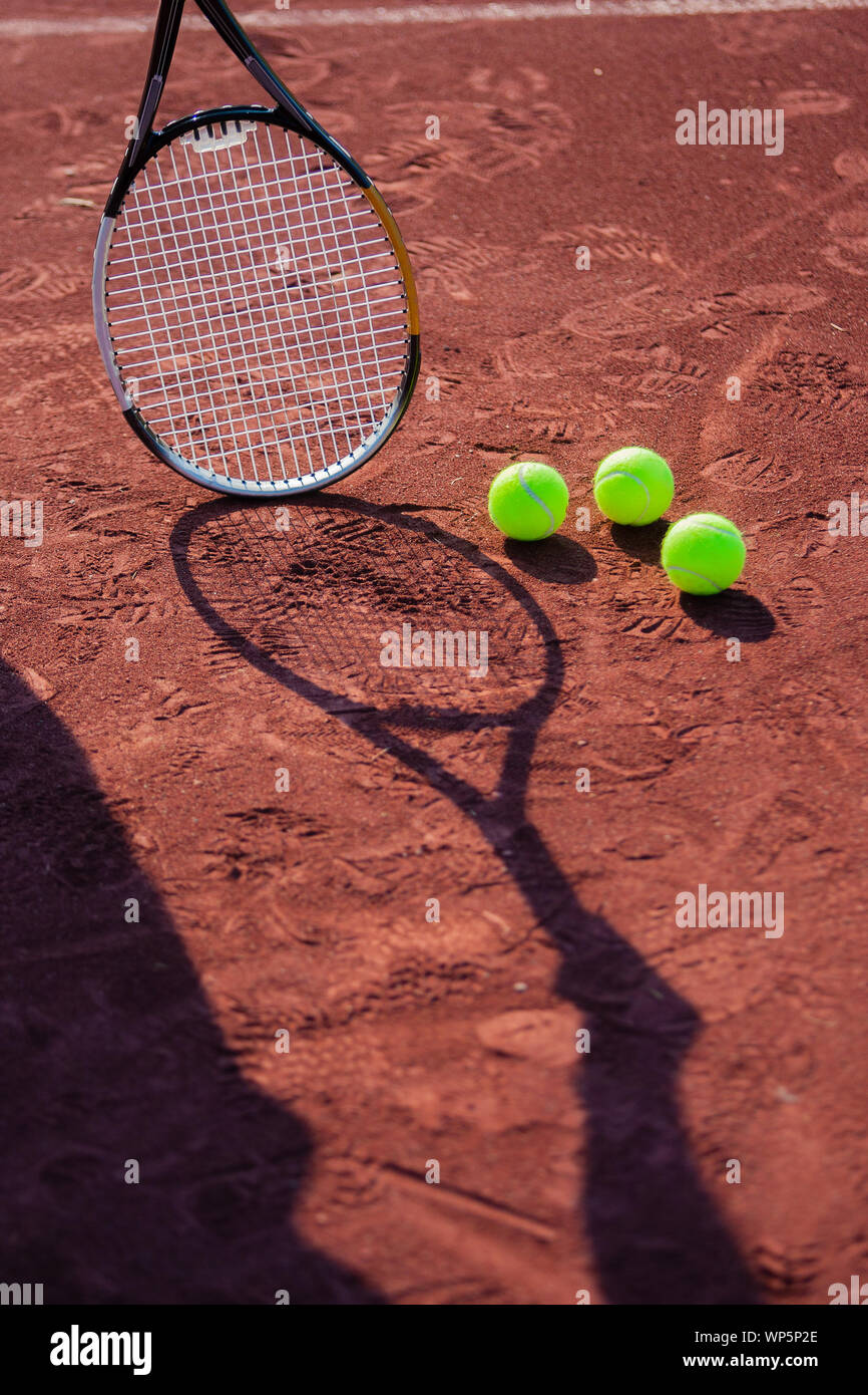 Ancora la vita di palle da tennis e l'ombra di una azienda di rman una racchetta da tennis su un campo da tennis in argilla rossa. Foto Stock