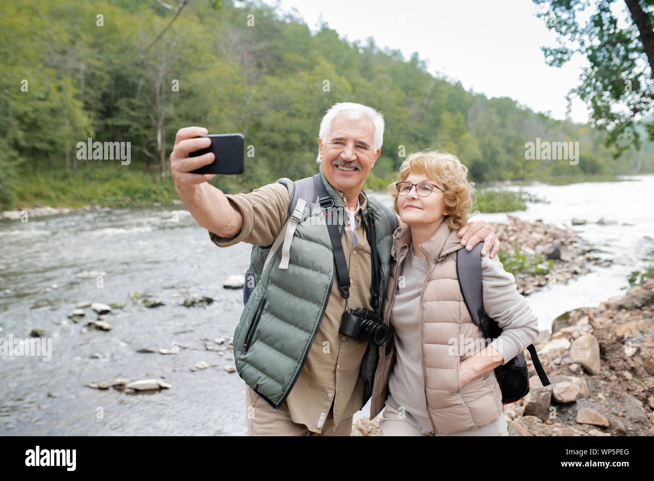 Felice coppia active coniugi guardando la fotocamera dello smartphone mentre si effettua selfie Foto Stock
