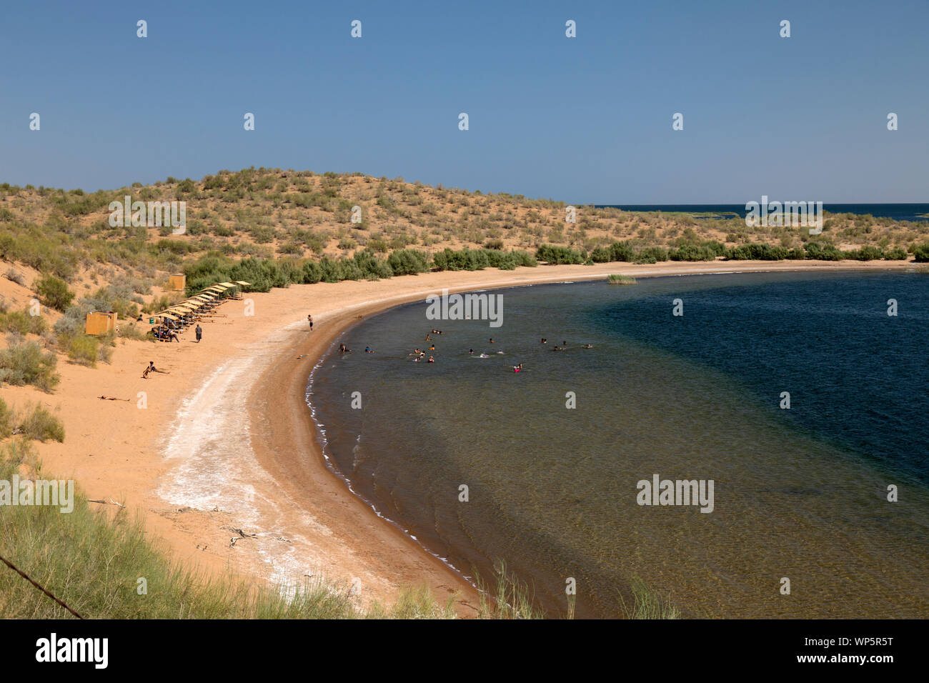 Una spiaggia di sabbia sulla sponda occidentale del Lago di Aidarkul vicino alla città di Nurata in Uzbekistan. persone il nuoto nel lago e prendere il sole. Foto Stock