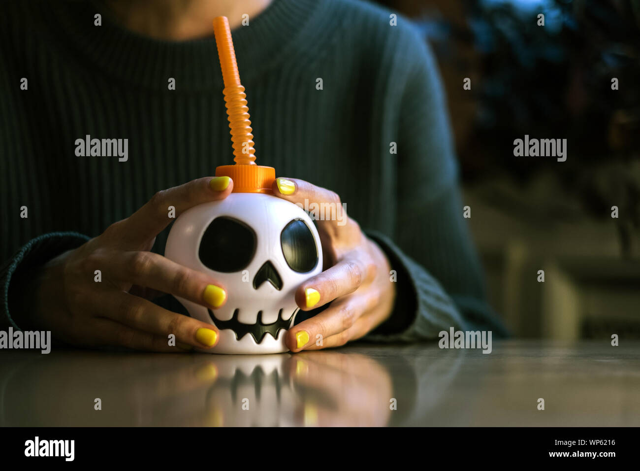 Anonimo mani con manicure tenere una tazza con un cranio in Halloween Foto Stock