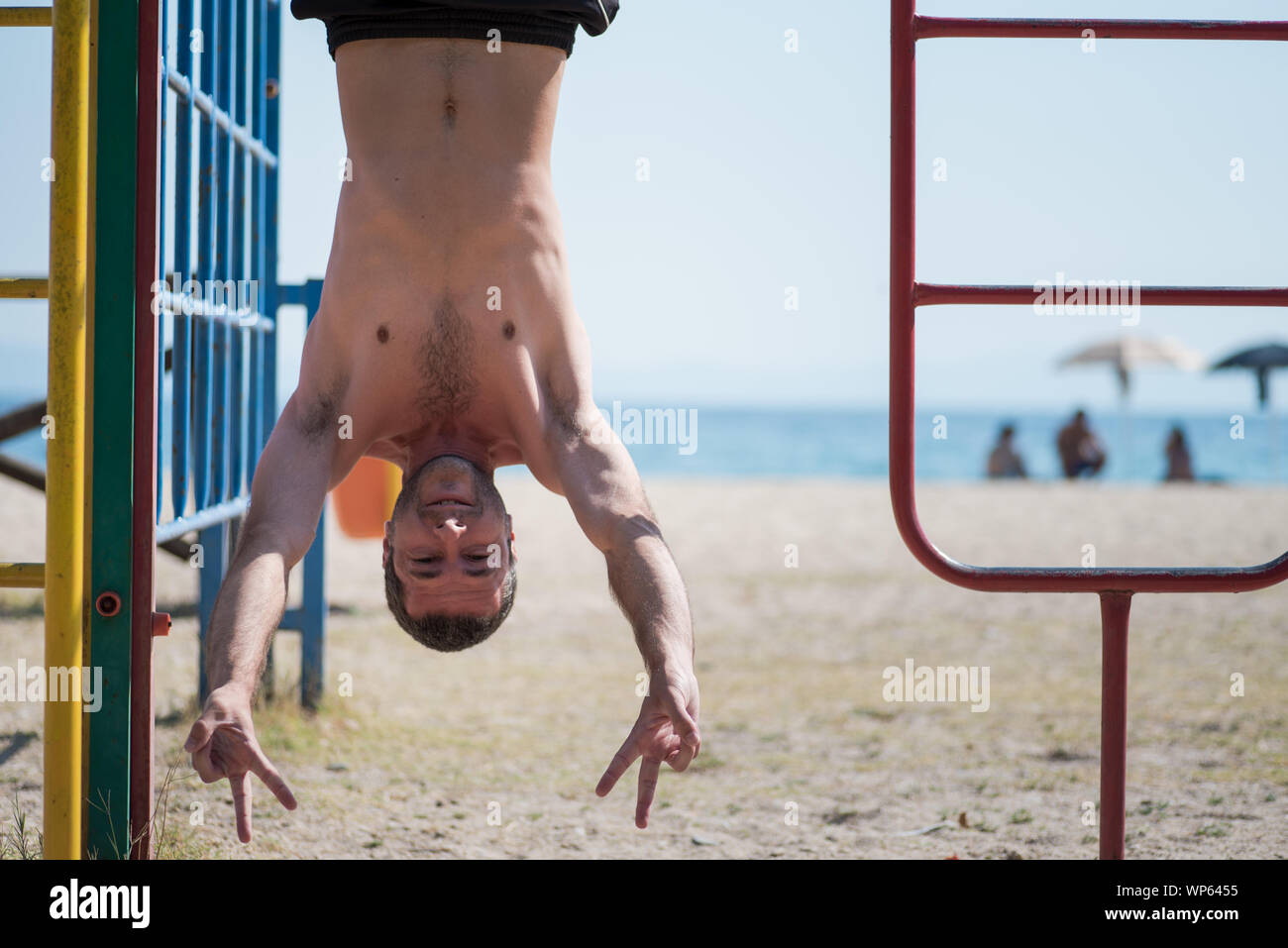 L'uomo appeso a testa in giù in spiaggia in Grecia Foto Stock