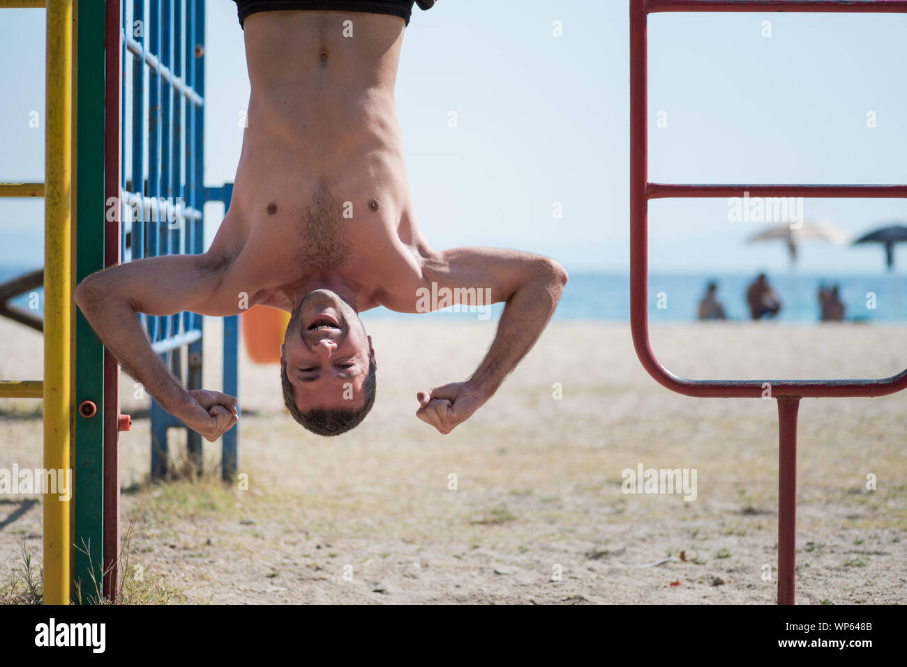 L'uomo appeso a testa in giù in spiaggia in Grecia Foto Stock