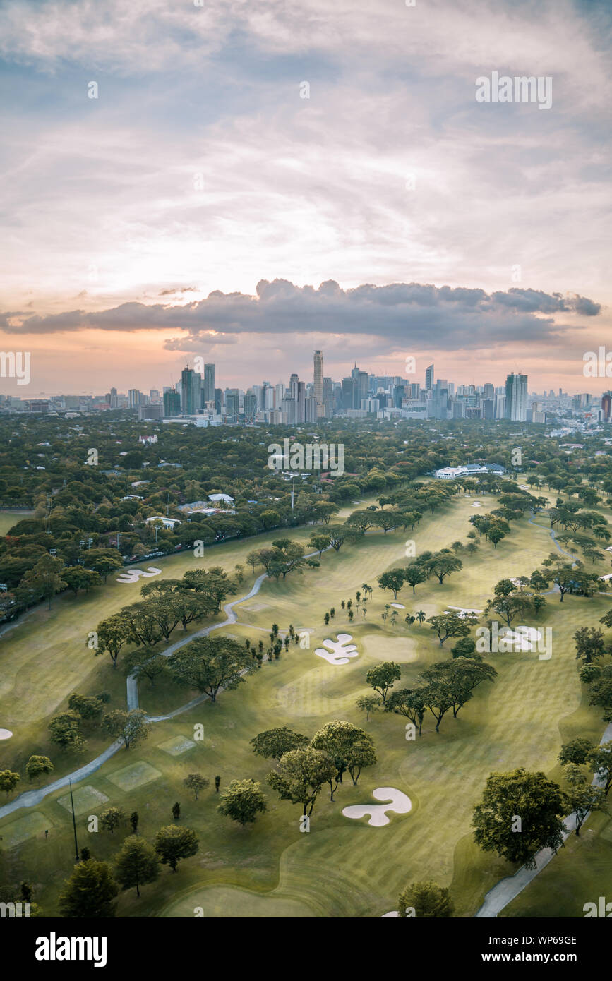Campo da golf e lo skyline di Manila, Filippine, in un bellissimo tramonto. Foto Stock