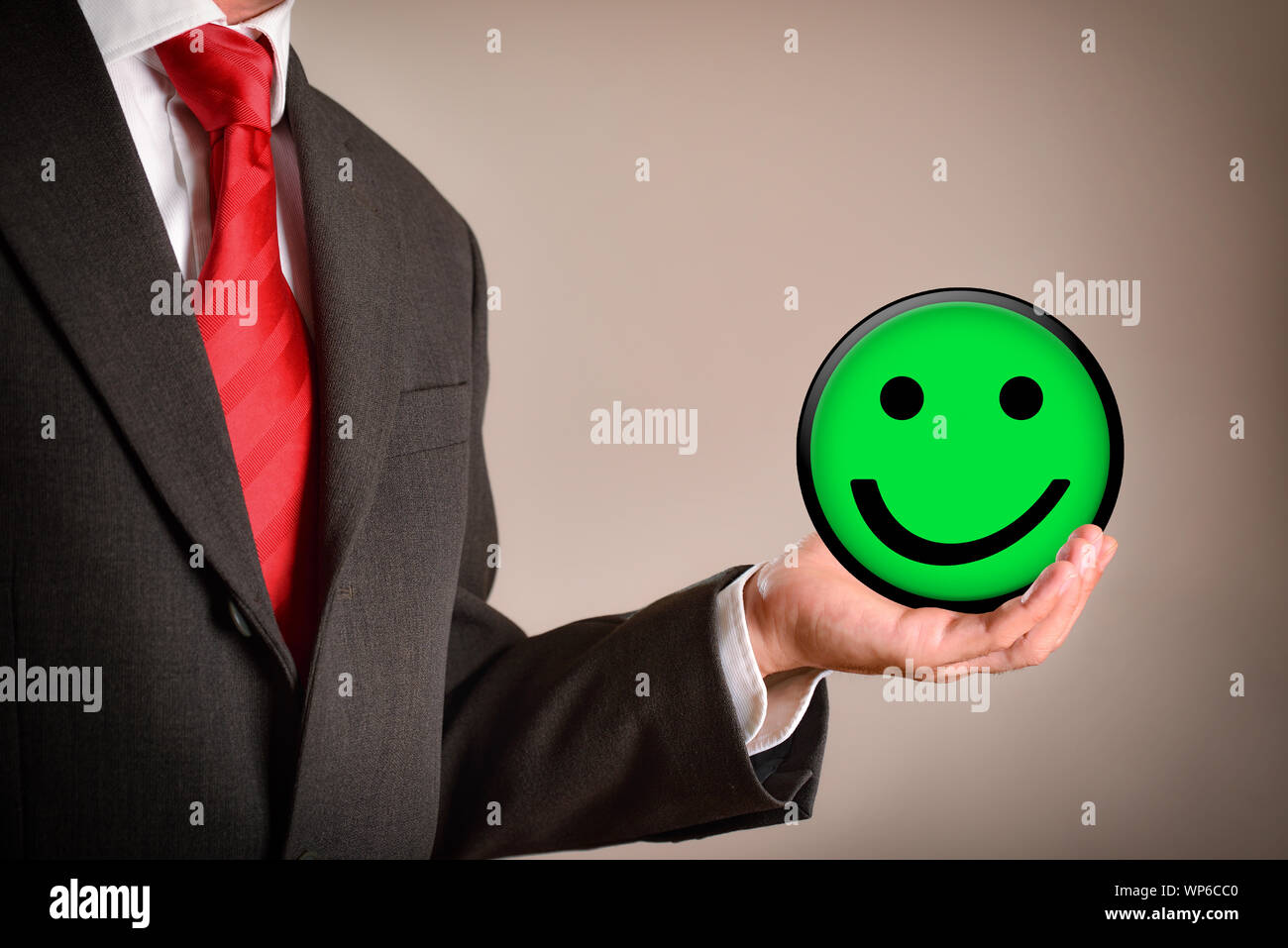 Imprenditore con emoticon in una mano. Concetto di successo. Composizione orizzontale. Vista laterale. Foto Stock