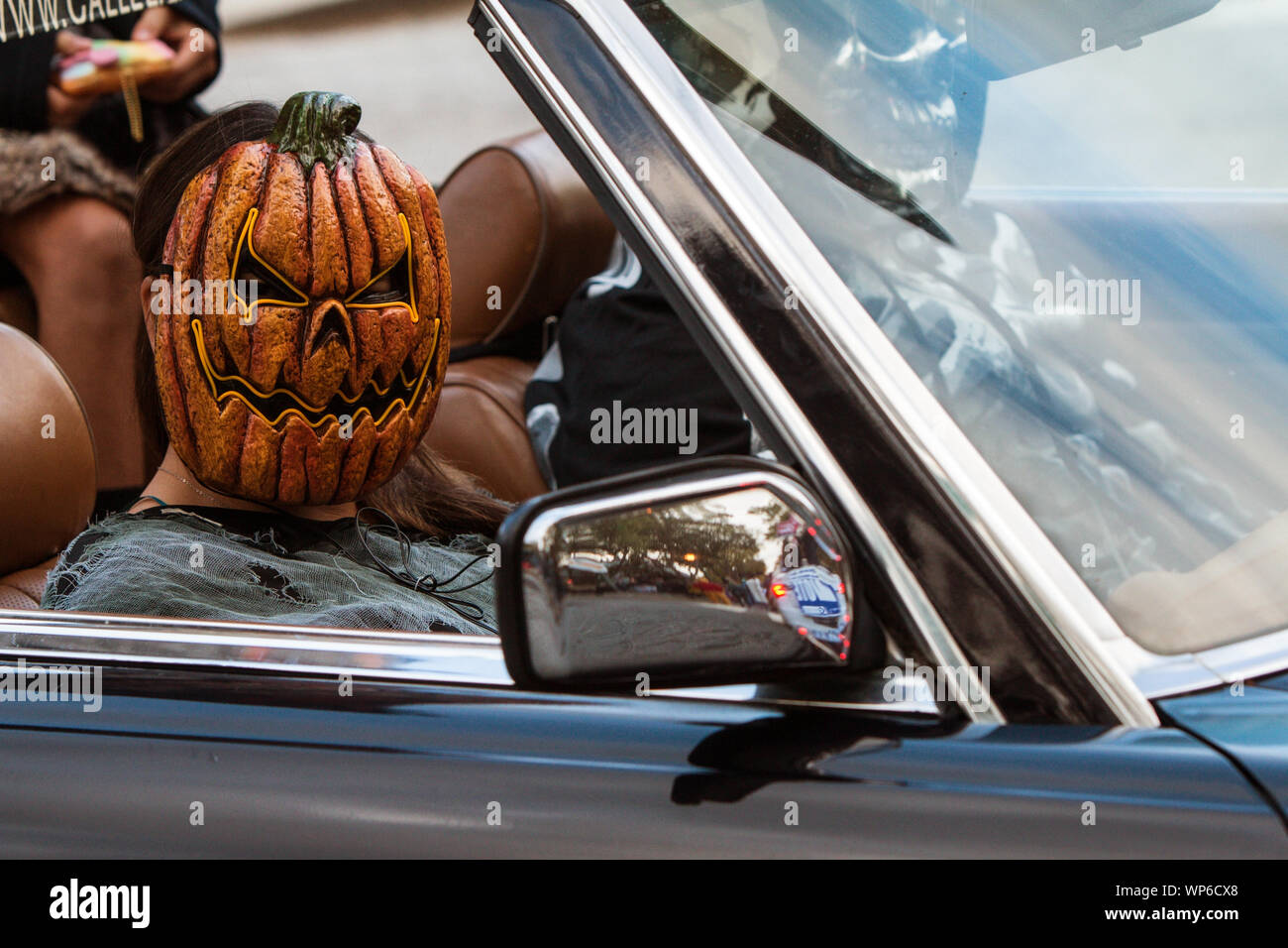 Una ragazza che indossa un inquietante maschera di zucca scorre in un convertibile al Haints e santi Halloween Parade su ottobre 27, 2018 in Decatur, GA. Foto Stock