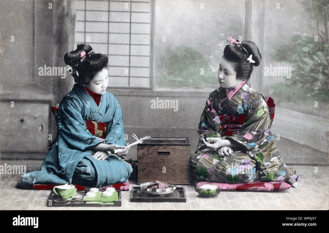 [ 1910s Giappone - Le donne giapponesi in kimono ] - Due giovani donne in kimono e acconciature tradizionale avente il tè. La donna a sinistra è in possesso di bastoncini. Xx secolo cartolina vintage. Foto Stock