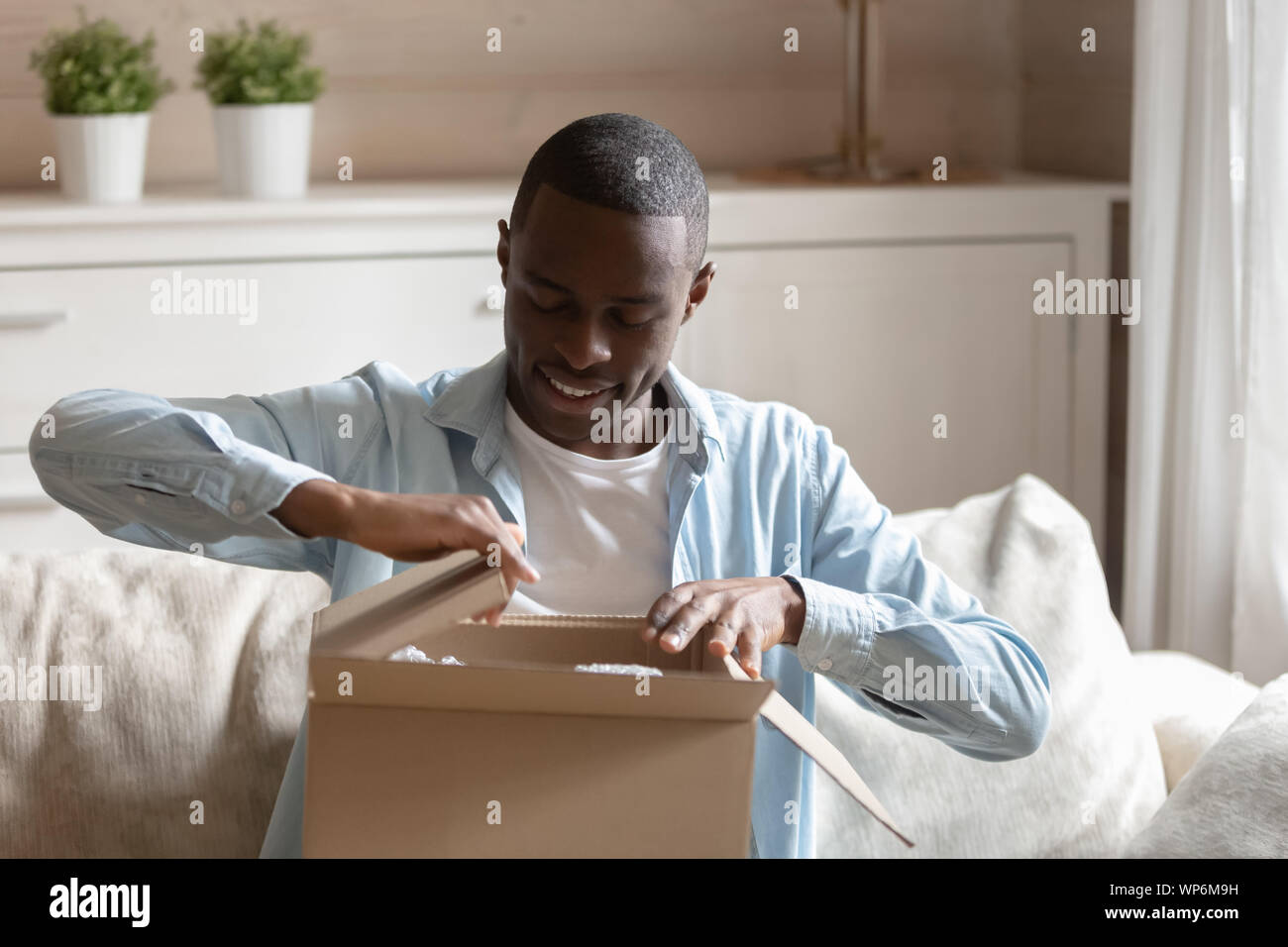 Felice biracial client maschio disimballaggio scatola di consegna Foto Stock