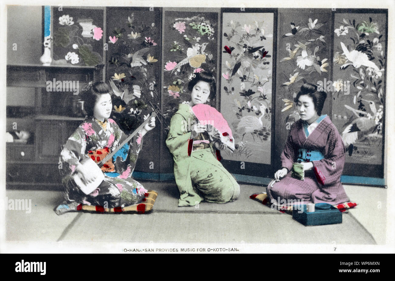[ 1900 Giappone - Le donne giapponesi godendo musica ] - Un giorno nella vita di una giovane donna giapponese durante la Meiji e Taisho periodi nei primi anni del XX secolo: 7. O-HANA-SAN offre musica per O-Koto-SAN. Xx secolo cartolina vintage. Foto Stock