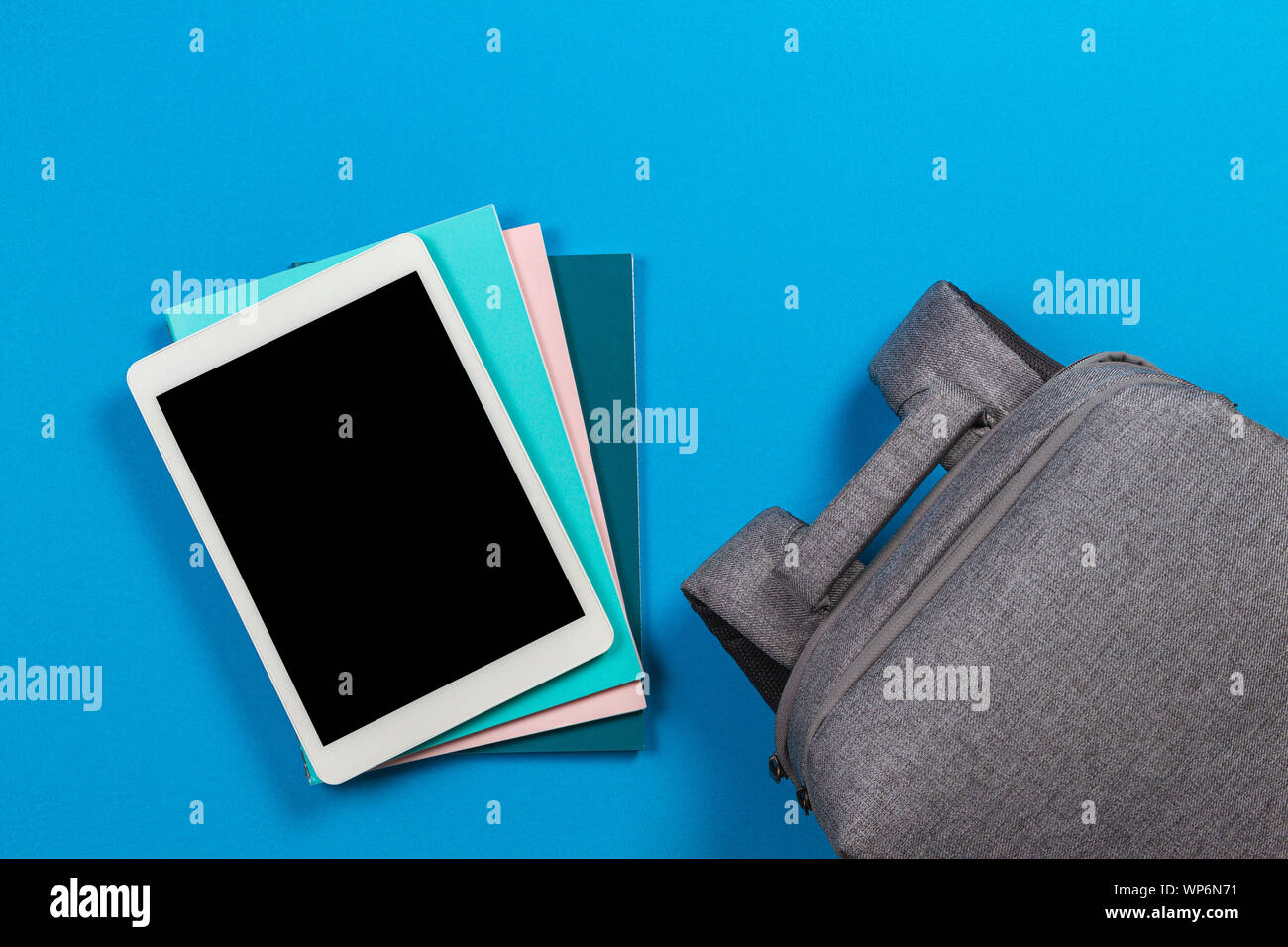 L'E-learning concetto - bianco tablet pc sulla parte superiore della pila  di libri colorati e notebook e uno zaino su sfondo blu Foto stock - Alamy
