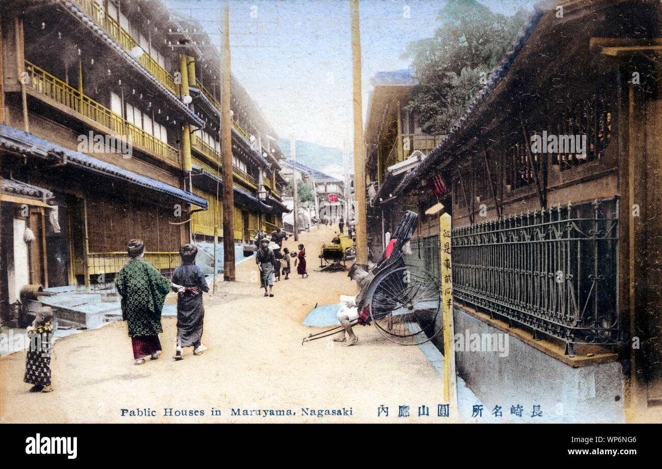 [ 1910s Giappone - bordelli a Nagasaki il distretto a luci rosse ] - La prostituzione distretto di Maruyama (丸山町) in Nagasaki. Un jinrikisha (rickshaw) estrattore si siede nel suo rickshaw, le donne e i bambini a piedi sulla strada fiancheggiata con tre storia bordelli. Xx secolo cartolina vintage. Foto Stock