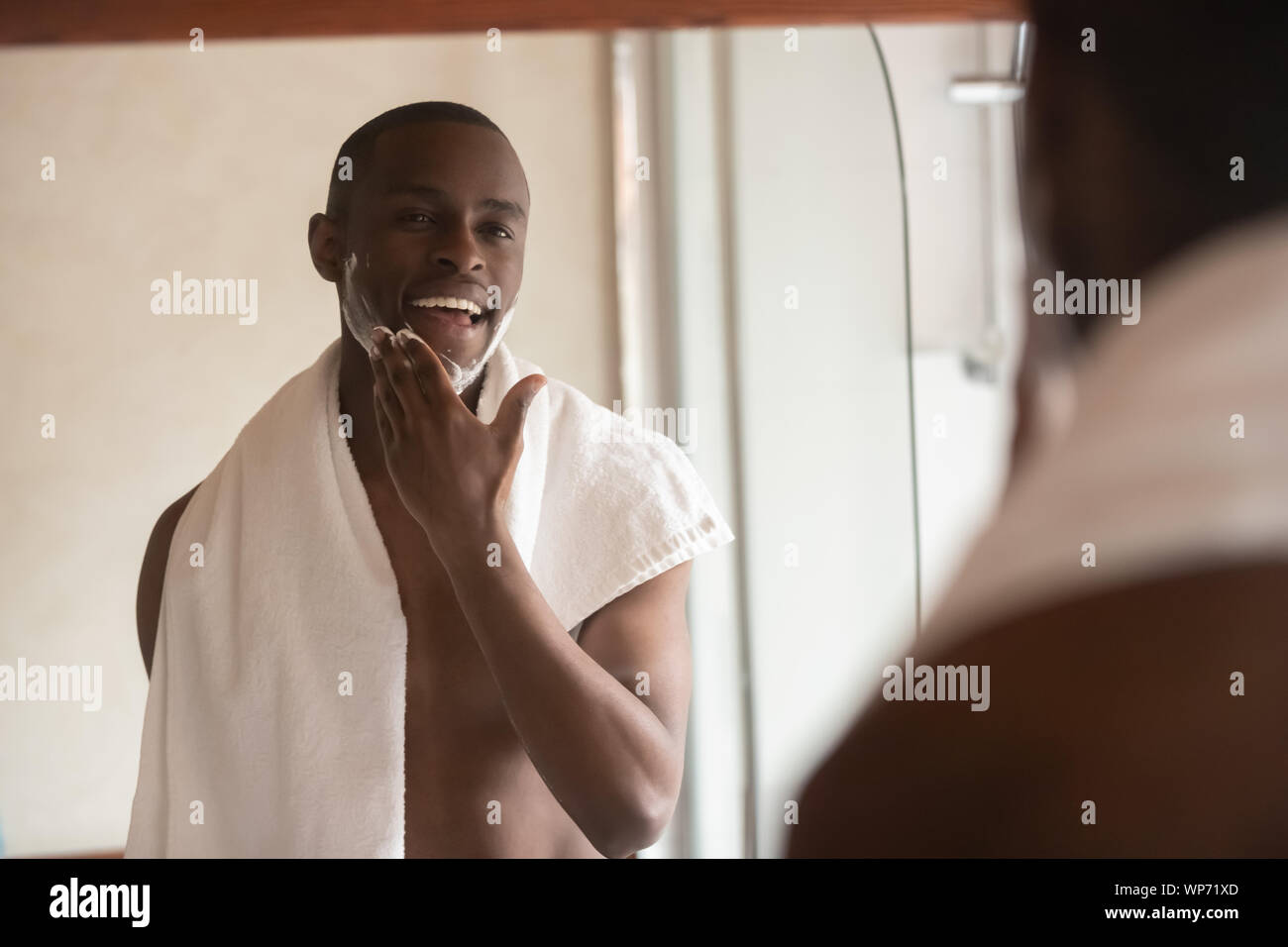 African American uomo applicare il balsamo per la rasatura in vasca da bagno Foto Stock