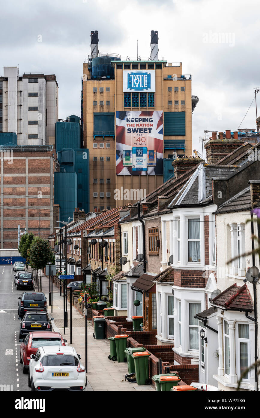 Tate & Lyle suger raffineria in fabbrica Silvertown, London, Regno Unito che domina le strade locali e case. Segno pubblicità e mantenendo la nazione dolce Foto Stock