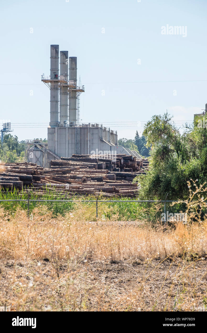 Un grande mulino di legname nel sud della Oregon con tre grandi pile di fumo e plles di tronchi di alberi pronti per l'elaborazione in primo piano. Foto Stock