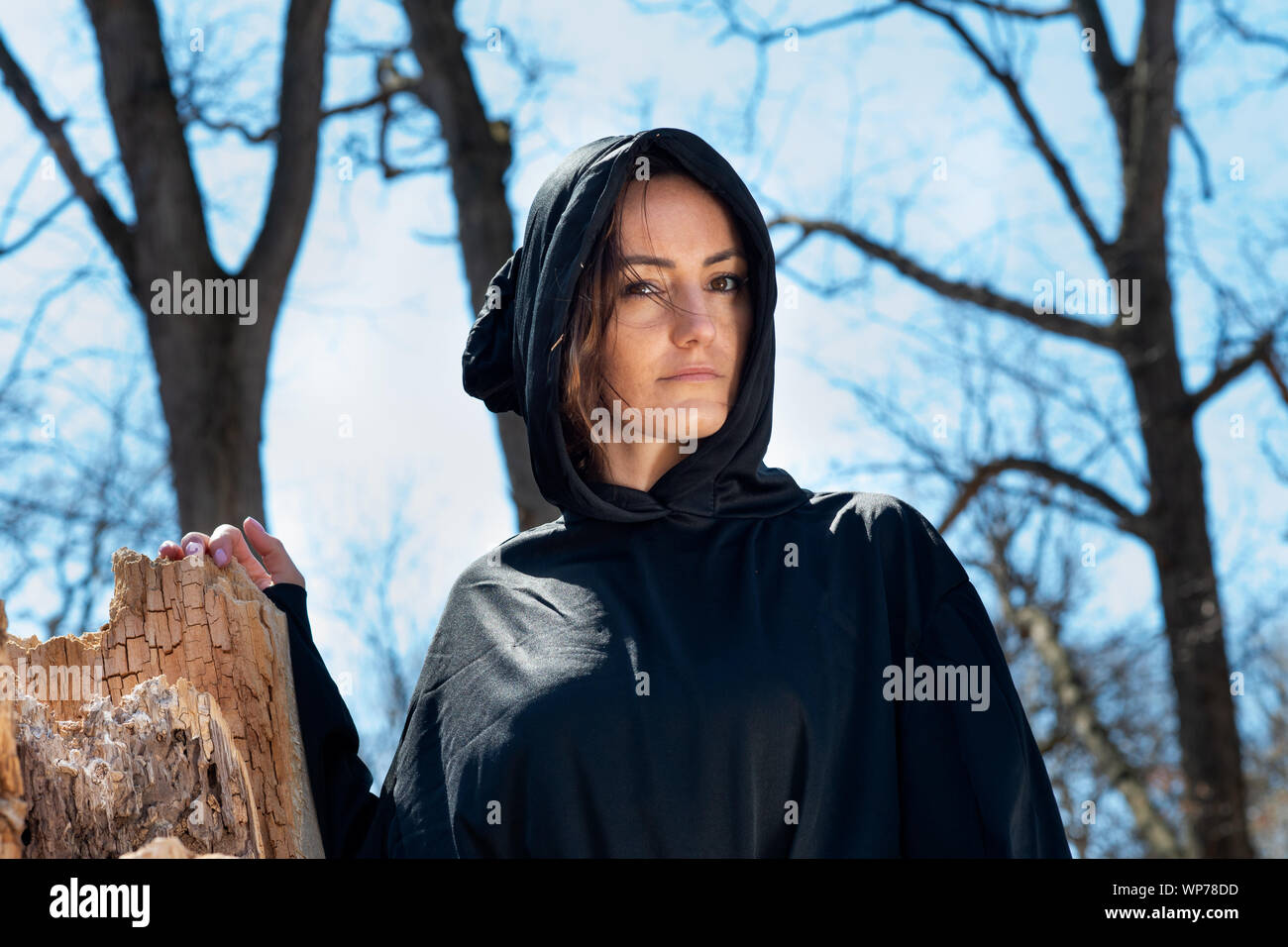 Donna con cappuccio in black robes nel profondo della foresta. Streghe. Halloween e concezione gotica. La stregoneria e magia. Scary. Foto Stock