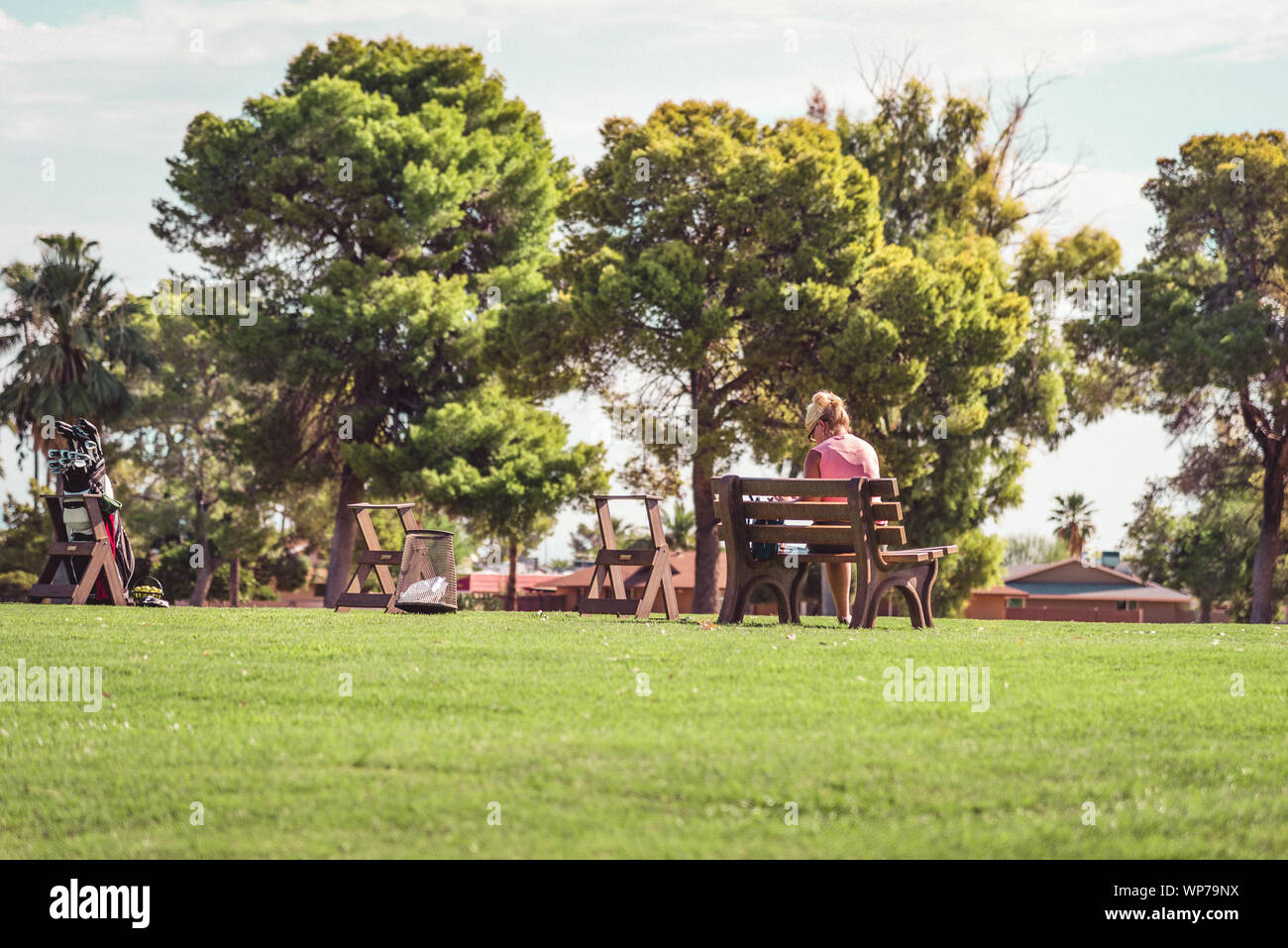 Analogico immagine dello stile di vita di un pensionato di donna seduta su un campo da golf a banco da parte del campo da golf. Sun City, Arizona. Foto Stock