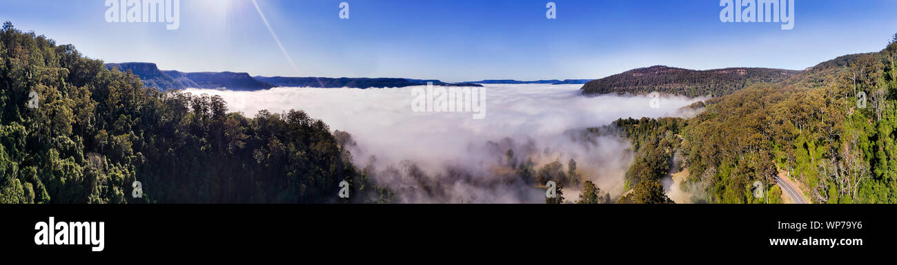 Kangaroo Valley in Australia coperto da uno strato spesso di nebbia bianco formando nuvole tra cime delle montagne circostanti con gomma-tree boschi nel mattino morbido Foto Stock