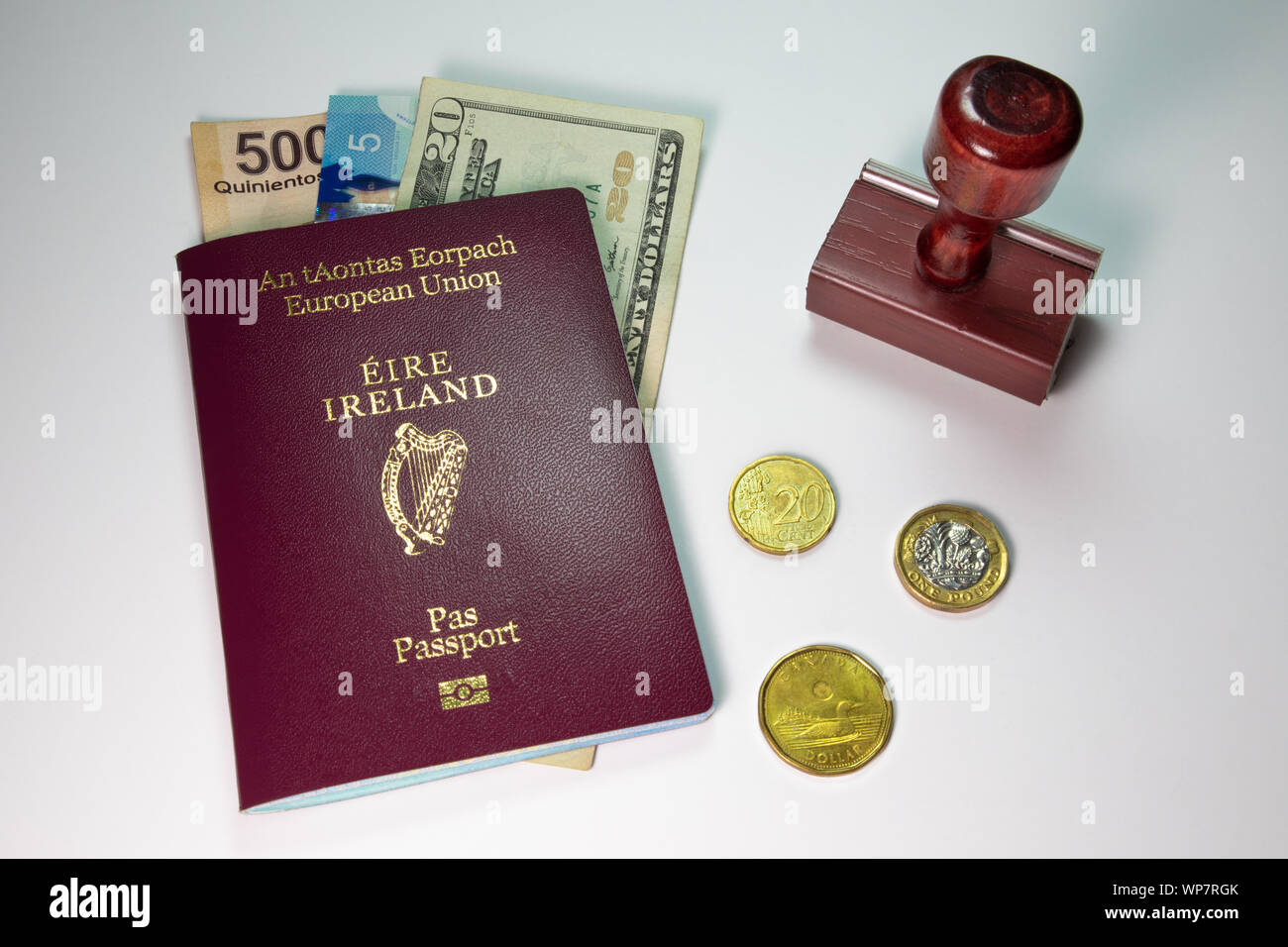 Concetto di viaggio con il rosso marrone rossiccio o colore borgogna passaporto irlandese, timbro e in valuta estera visualizzato su uno sfondo semplice Foto Stock