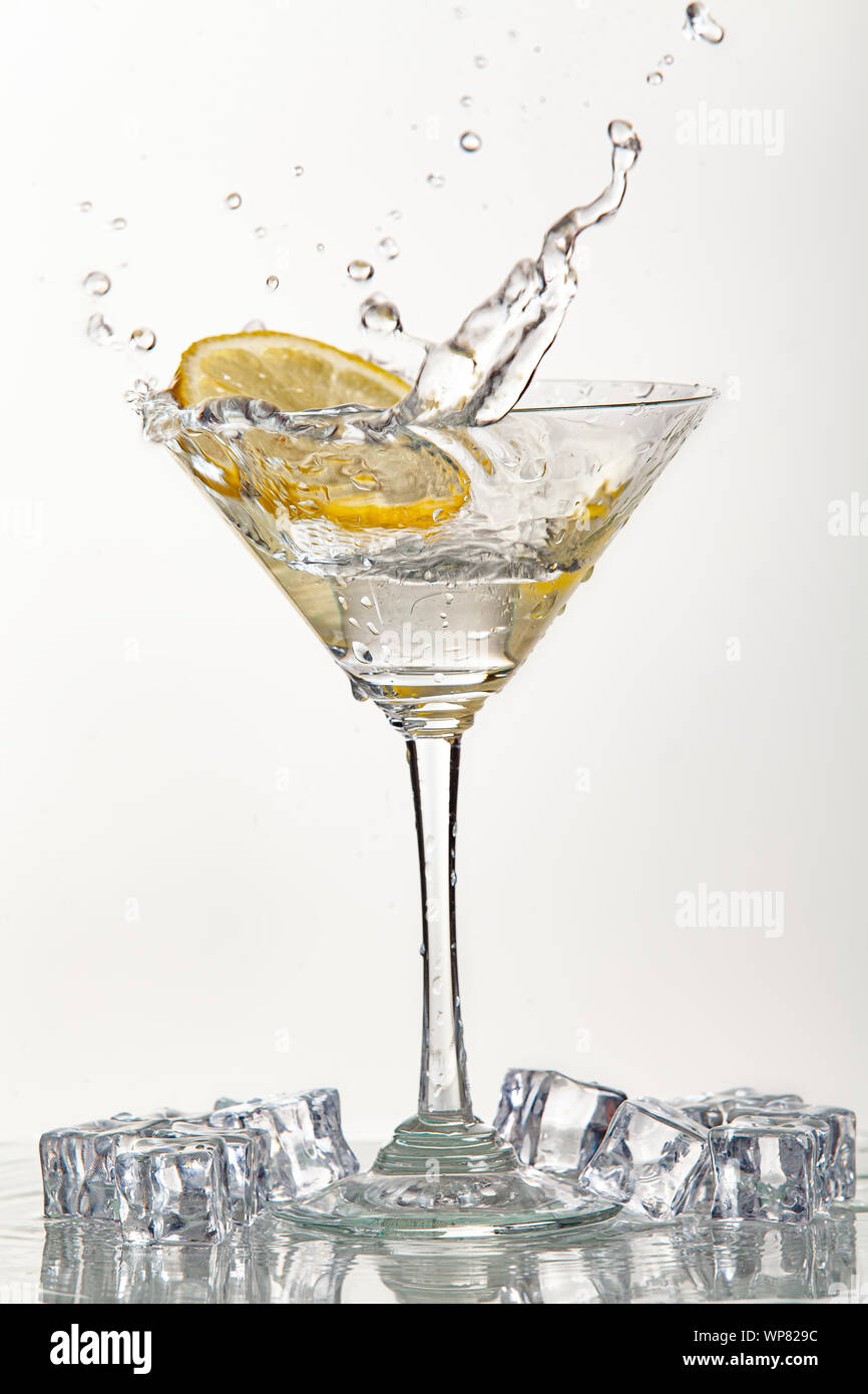 Bicchiere di acqua e limone e watersplashes su un nero di sfondo per studio Foto Stock