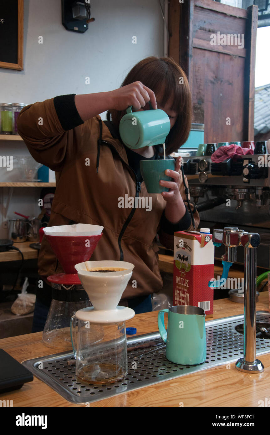 La donna la preparazione di caffè, prodotta localmente da-coltivati semi in Lijiang, Yunnan, Cina Foto Stock