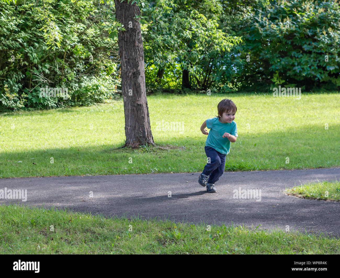 Un bambino di circa due anni fa una brusca svolta a decollare in esecuzione su un percorso in un parco pubblico. Foto Stock