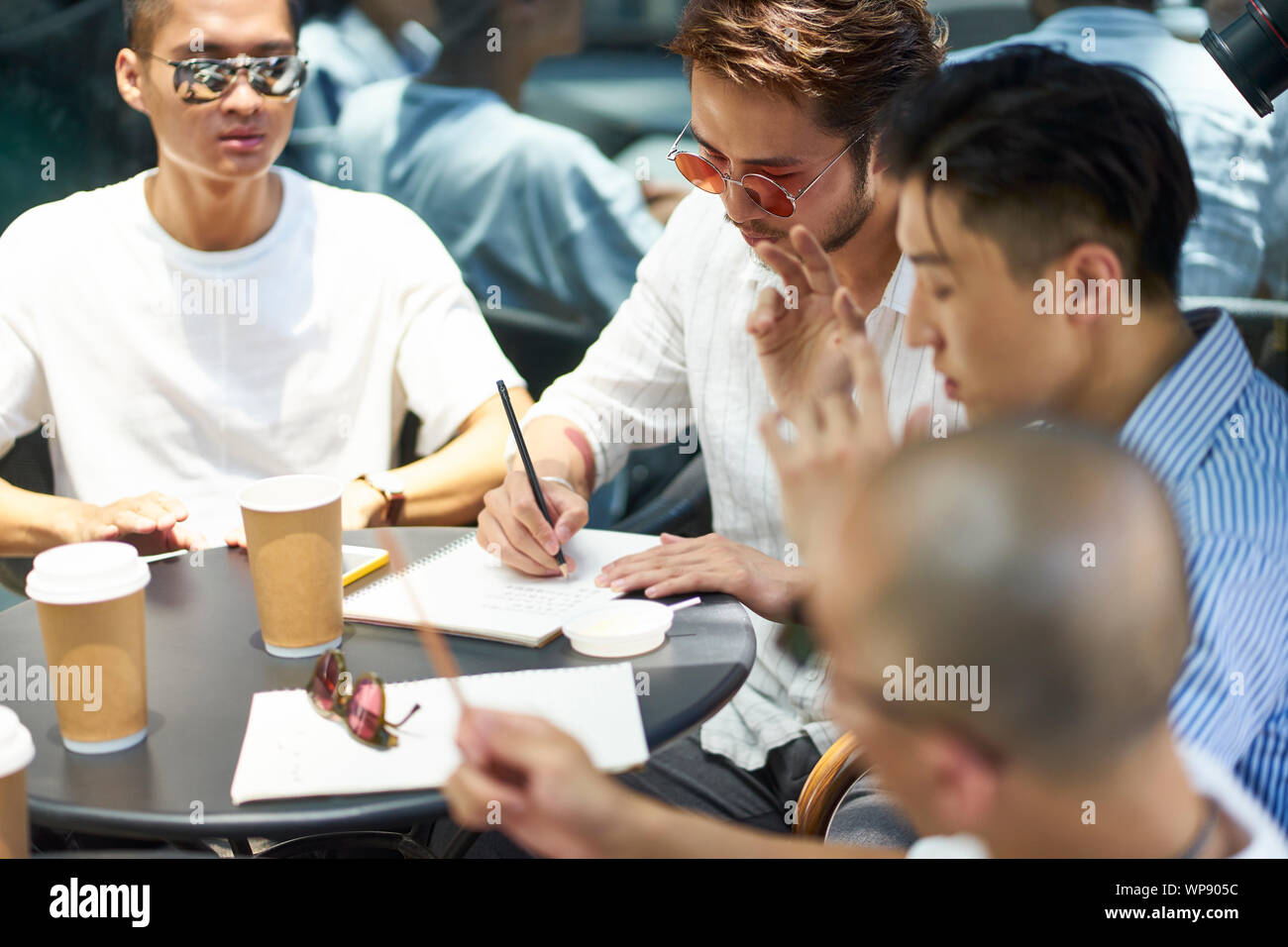 Un gruppo di giovani asiatici gli studenti universitari che studiano insieme in una piscina caffetteria Foto Stock