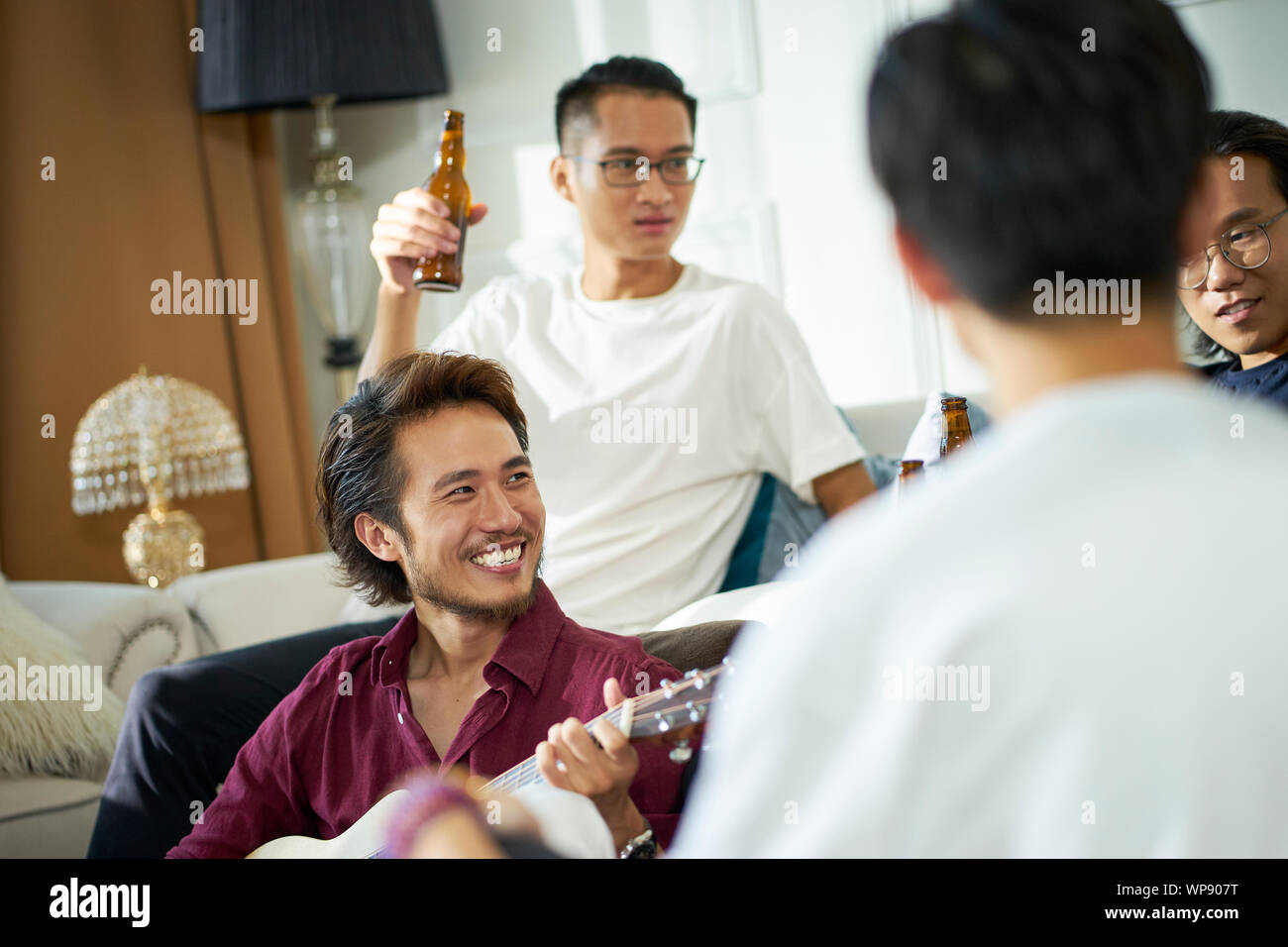 Giovani asiatici uomini adulti bere birra a casa Foto Stock