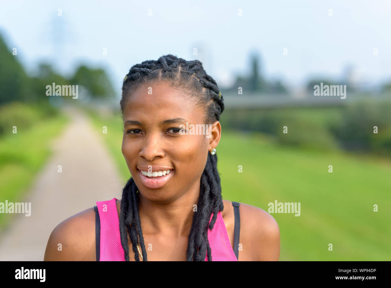 Felice giovane donna africana intrecciata con le estensioni di capelli svolta a guardare la fotocamera Foto Stock