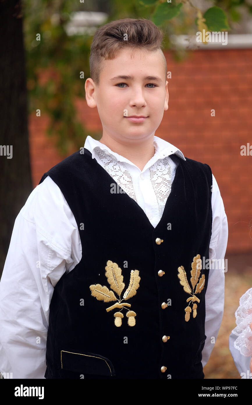 Ragazzo vestito in costumi folcloristici andare in chiesa durante la Santa Messa il giorno del Ringraziamento in Stitar, Croazia Foto Stock